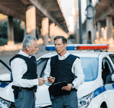 Two policemen in front of a police car. 