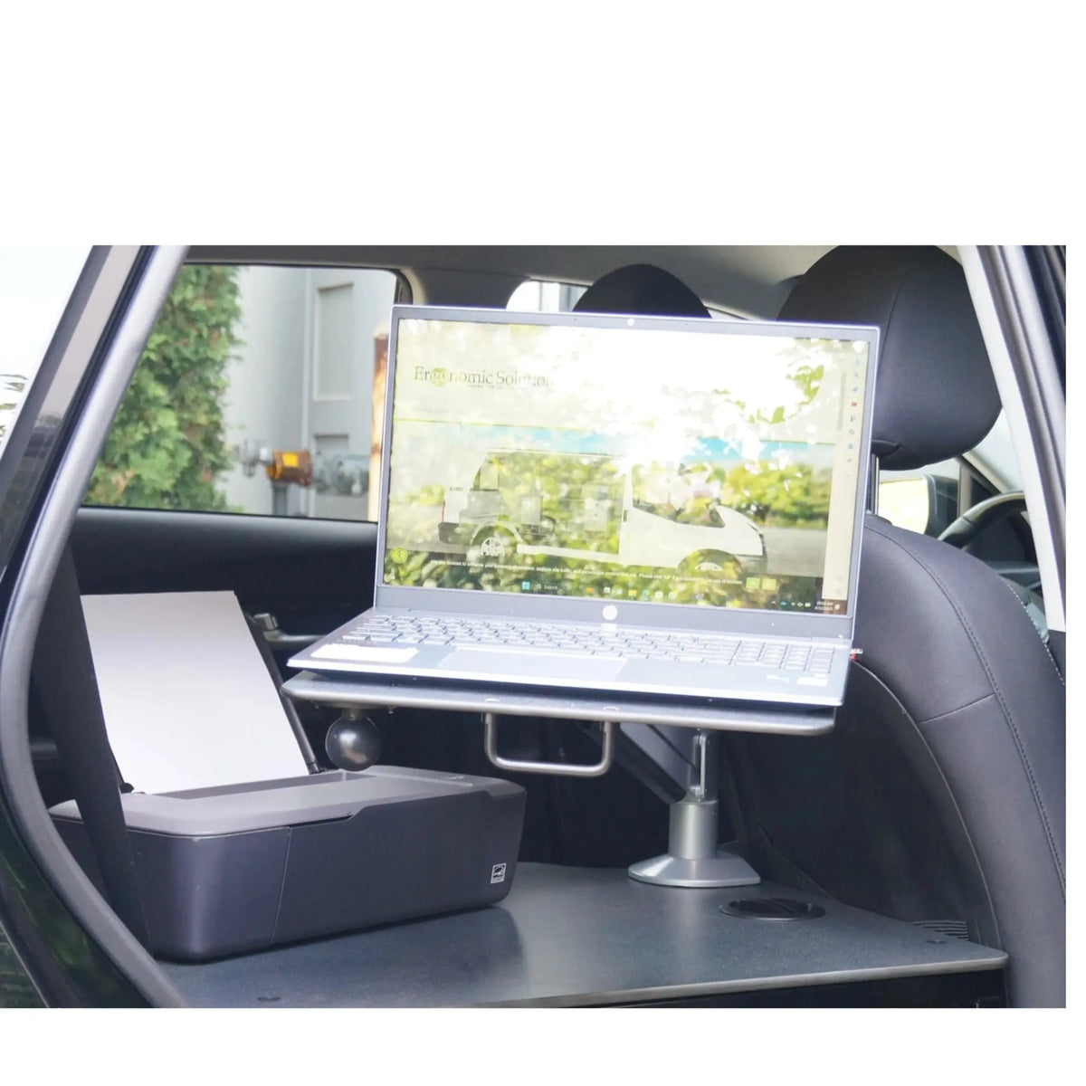 Laptop sitting on extension arm while there is a printer on the desk.