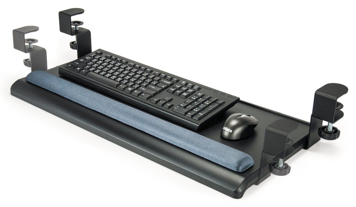 a black keyboard tray designed to attach under a desk. It features a flat, rectangular surface with rounded corners and a padded wrist rest along its front edge. The tray is supported by two metal clamps on either side, for adjusting as necessary. A black standard keyboard and gray wireless rest on the surface