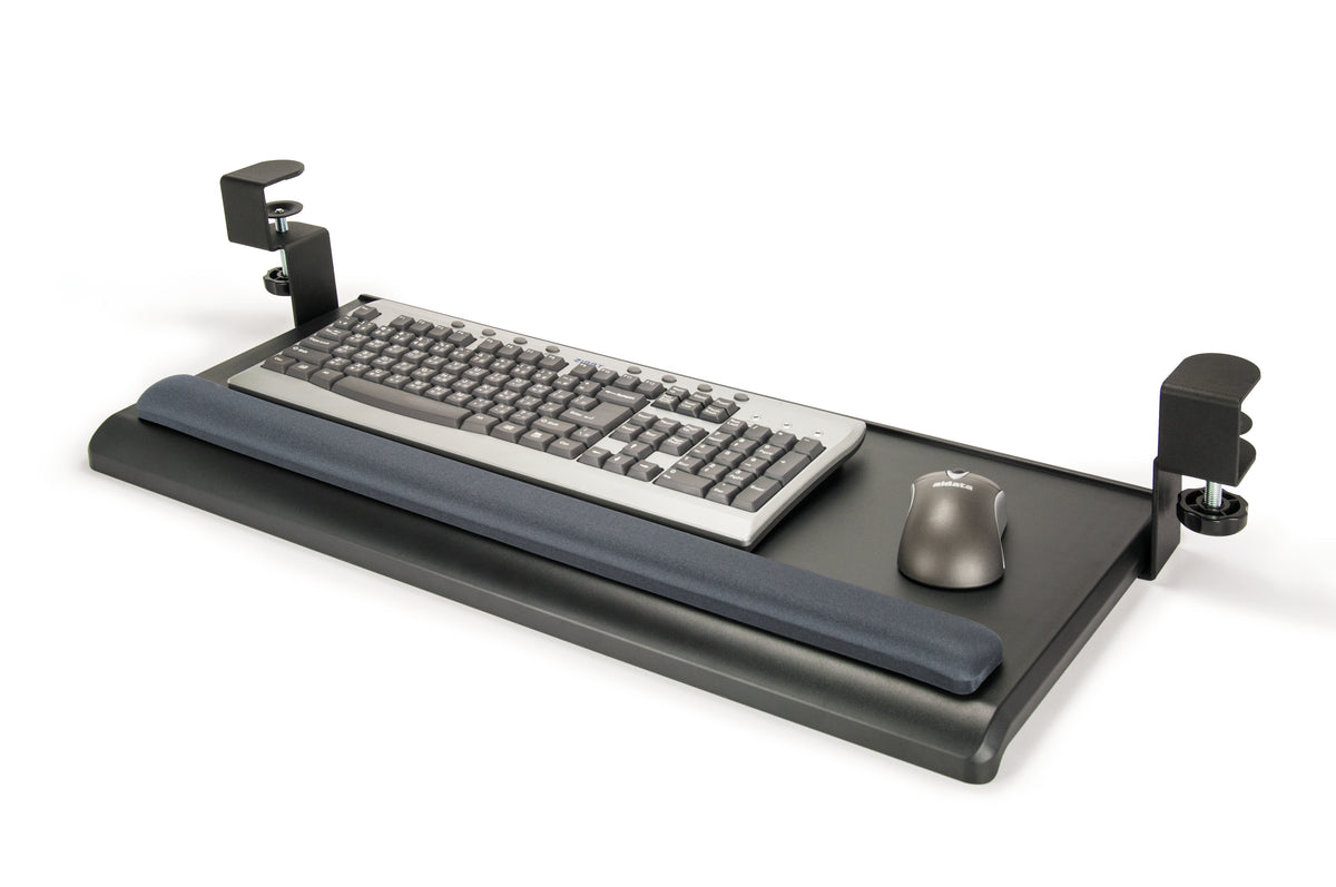 a black keyboard tray designed to attach under a desk. It features a flat, rectangular surface with rounded corners and a padded wrist rest along its front edge. The tray is supported by two metal clamps on either side, for adjusting as necessary. A sliver standard keyboard and black wireless rest on the surface