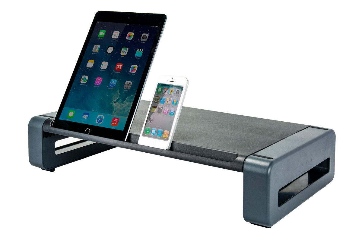 a rectangular monitor stand with a black surface tray and a gray stand. A black vertical iPad and White iPhone rest in a small slot at the front