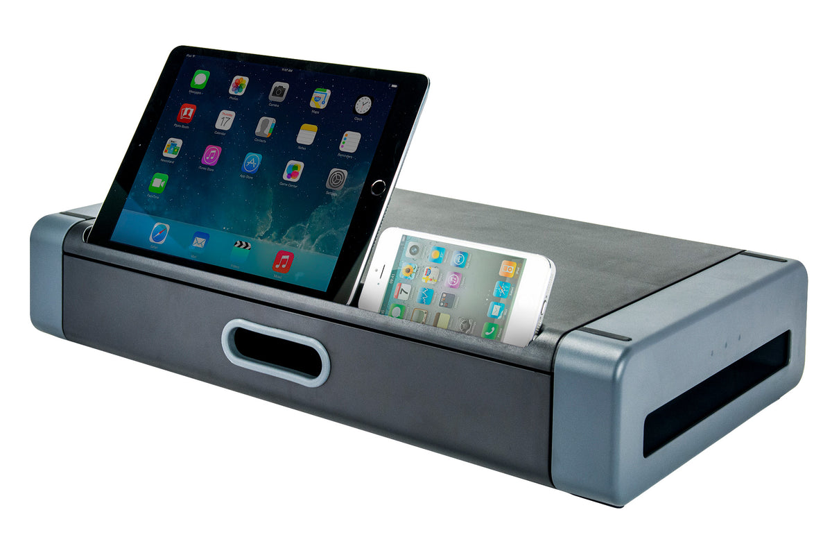 a gray and black plastic rectangular monitor stand and storage drawer with a flat top surface and two openings on the front side: an oval shaped handle and a long divot holding a black iPad and a white iPhone, both screens have colorful apps