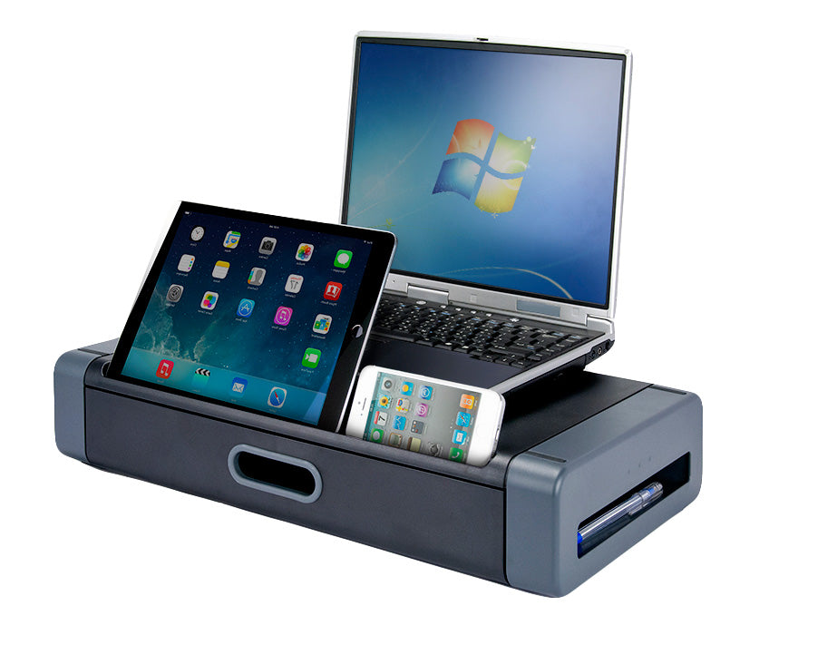 a gray and black plastic rectangular monitor stand and storage drawer with a flat top surface and two openings on the front side: an oval shaped handle and a long divot holding a black iPad and a white iPhone, both screens have colorful apps. A silver and black laptop computer rests on the top