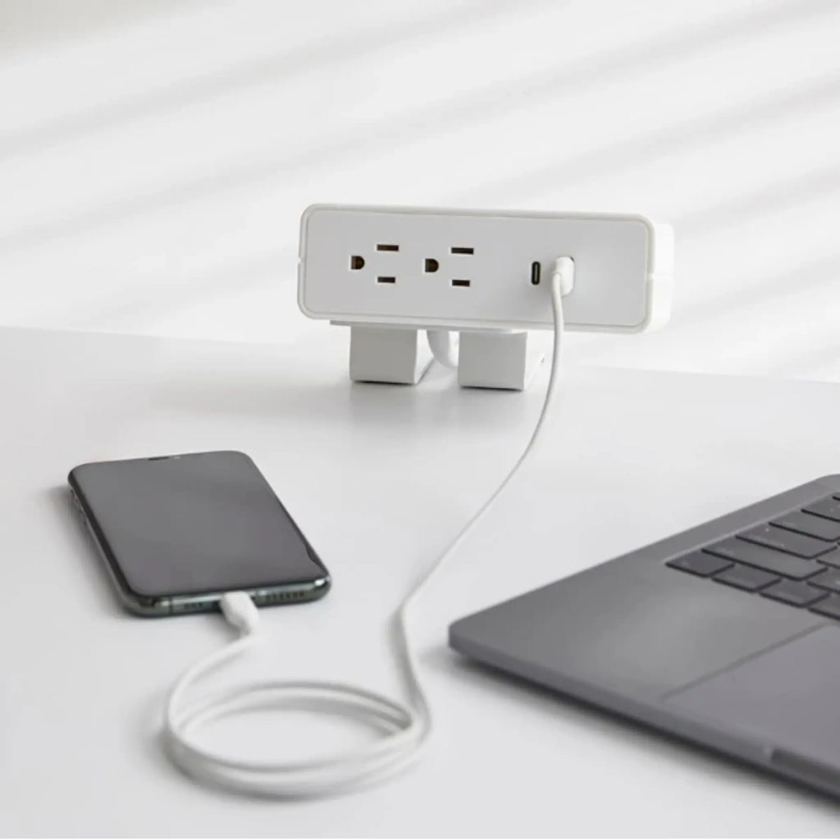 White NeatHub Power Station in use on a wood desk plugged into a portable phone.