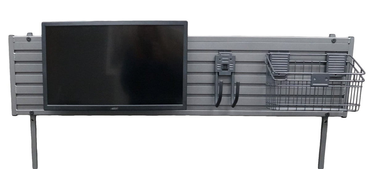 a long ridged piece of silver metal with 2 long metal posts, designed to mount to a desk, screwed to each end. A black computer monitor is mounted to length of metal on the left side, a j shaped hook is mounted in the middle, and a medium sized black metal basket mounted on the far right