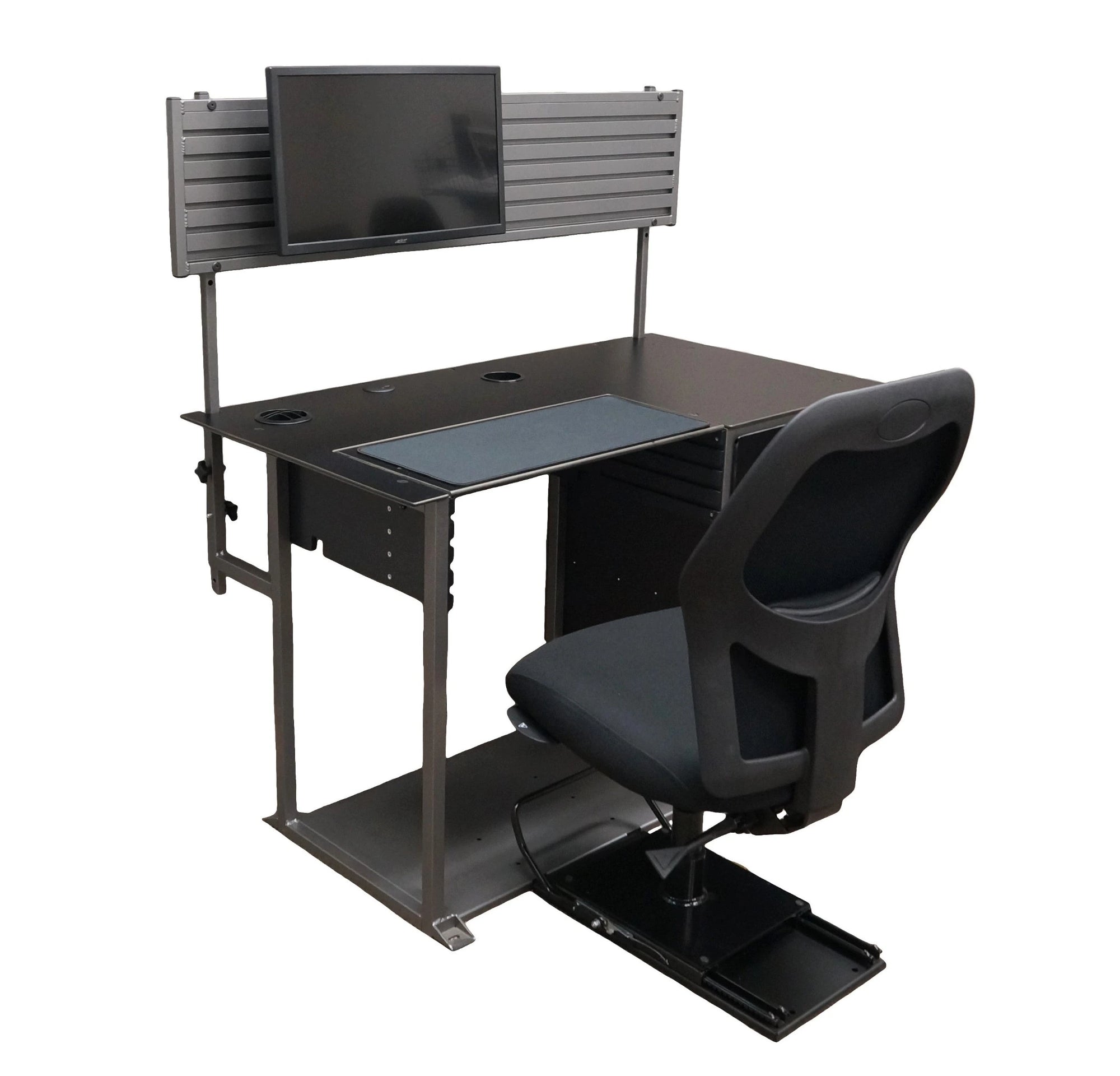 a right-angled view of a small black desk, a gray metal hutch with a monitor, hook, and basket, and a black chair mounted on a sliding seat base. It has a silver metal frame and a set of drawers on the right side. The work surface has 2 grommet holes, a white box, and a sheet of black fabric in the middle for a keyboard and mouse. The hutch is mounted to the desk with metal poles on the back. The bottom is connected together with a large sheet of gray metal to which the sliding black chair is mounted. 