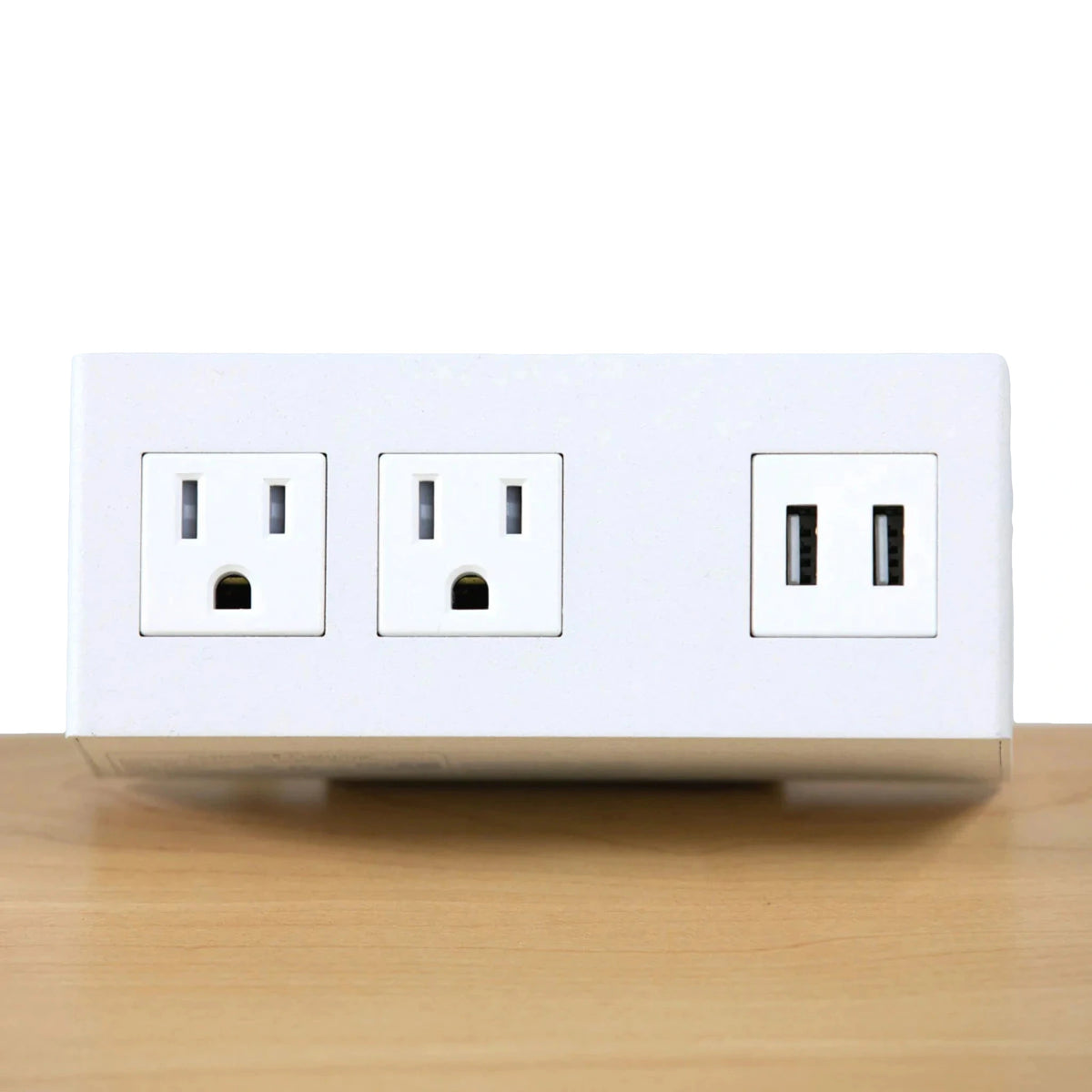 a white dual electrical outlet and a USB port installed on a light-colored wooden desk for easy access to power and USB charging options